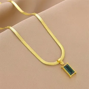 Detailed view of a gold titanium steel necklace with a green emerald-cut pendant.
