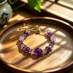 Handmade natural amethyst beaded bracelet with adjustable gold-tone chain on wooden tray