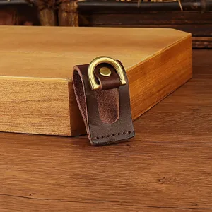 Close-up detail of genuine leather belt key holder featuring brass D-ring and metal rivet.