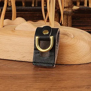 Close-up detail of black leather belt key holder with gold D-ring and metal snap.
