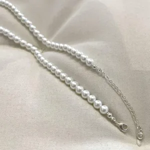 Detailaufnahme einer weißen Perlenkette mit silbernem Karabinerverschluss und Verlängerung.