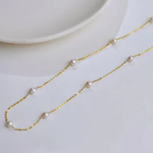 Detaillierte Makroansicht einer eleganten Goldkette mit weißen Perlen-Akzenten.