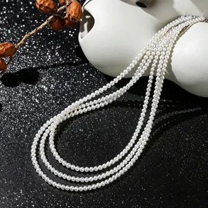 Gros plan détaillé montrant la texture lustrée d'un collier de perles blanches à plusieurs rangs.