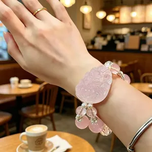 Nahaufnahme eines natürlichen Rosenquarz-Armbands mit einem fein geschnitzten Fuchs-Anhänger.
