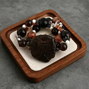 Detailansicht eines Armbands aus Obsidian und Quarz mit geschnitztem Fuchsamulett