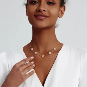 Elegante goldene Halskette mit weißen Perlenblumen-Anhängern an einem Model getragen