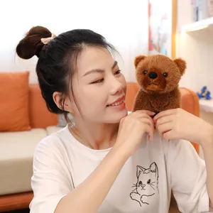 Petit ours en peluche marron réaliste tenu par un modèle, texture douce visible