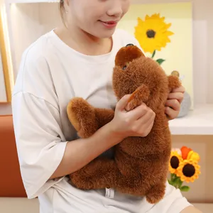 Ours en peluche marron doux tenu par une personne pour montrer la taille et le détail