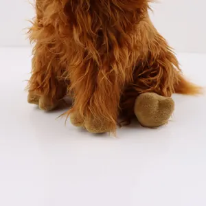 Détail de la longue fourrure brune réaliste et des pattes douces d'une peluche de vache écossaise