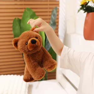 Vue détaillée de l'ours en peluche marron réaliste tenu par la main