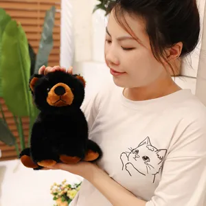 Détail montrant une personne tenant une petite peluche d'ours noir réaliste en cadeau