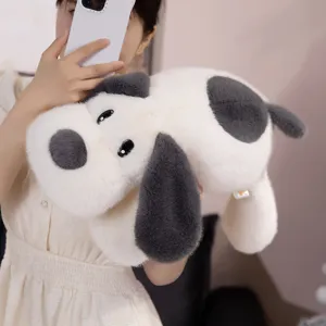 Peluche de chiot aux grandes oreilles gris et blanc, tenue par une personne pour l'échelle.