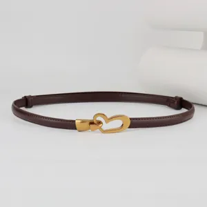 Close-up detail of the elegant dark brown thin leather belt with gold heart buckle.
