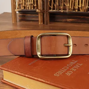 Close-up detail of retro brown leather belt with vintage metal pin buckle displayed on a book.