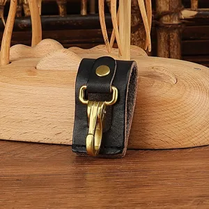 Detailed shot of black leather belt key holder with brass metal clasp, durable accessory.