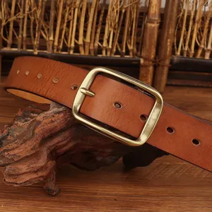 Close up of vintage brown leather belt with brass pin buckle on rustic wood surface detail.