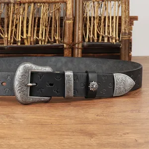 Detailed close-up of the vintage leather belt featuring ornate silver carved buckle and cross charm.