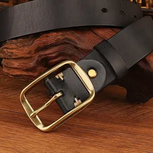 Detail view of a black leather belt with retro brass metal pin buckle and stitching.