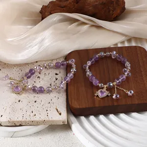 Detailaufnahme von lila Amethyst-Perlenarmbändern mit eleganten Strass-Herzanhängern