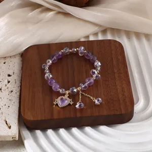 Nahaufnahme eines Armbands aus violettem Kristall mit einem glitzernden Herzanhänger.