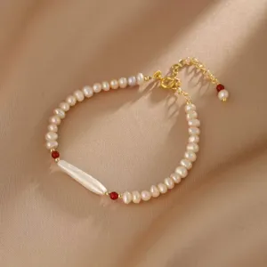 Nahaufnahme eines natürlichen Perlenarmbands mit roten Achatperlen und Goldkette