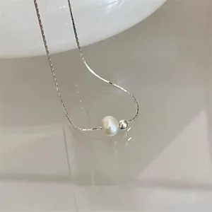 Detailansicht einer glänzenden Süßwasserperle an einer minimalistischen Silberkette