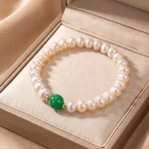 Close-up of a natural pearl bracelet with a green stone bead in a beige jewelry box