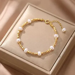 Detailed view of a gold-beaded bracelet with eight elegant white pearls on a gold box