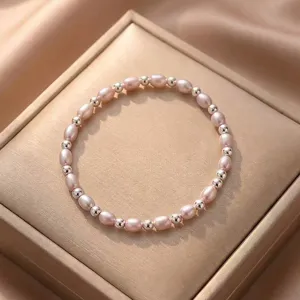 Detail view of a pink oval pearl and silver bead bracelet on a champagne jewelry box