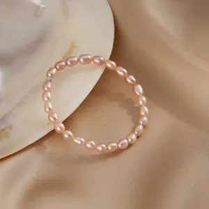 Macro detail shot of a natural pink freshwater pearl bracelet on satin with a seashell