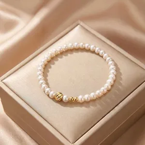 Close-up view of an elegant natural pearl bracelet featuring gold bead accents on a silk box.