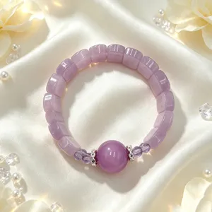 Nahaufnahme eines lila Kristallarmbands mit Diamant-Abstandshaltern auf weißer Seide.