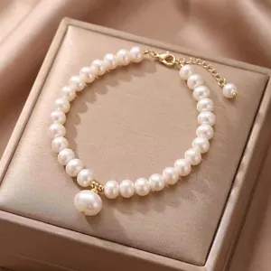Detailed view of elegant natural pearl bracelet with gold hardware on a silk display