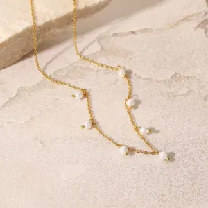 Detaillierte Nahaufnahme einer Goldkette mit eleganten Süßwasserperlen auf Stein.