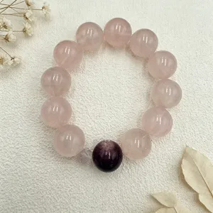 Detailansicht eines Rosenquarz-Armbands mit lila Akzentperle auf Strukturstoff