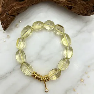 Makroansicht von gelben Kristallperlen und goldfarbenen Abstandsperlen auf Marmor