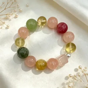 Detailansicht eines bunten Naturkristall-Armbands auf elegantem weißem Satinstoff präsentiert.