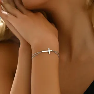 Detailaufnahme eines minimalistischen silbernen Armbands mit seitlichem Kreuzanhänger am Handgelenk