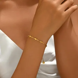 Detailaufnahme eines goldenen Kettenarmbandes mit Kreuzanhängern am Handgelenk