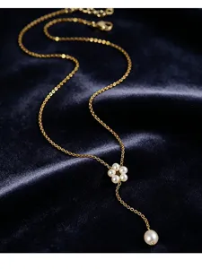 Nahaufnahme einer goldenen Blumenkette mit Süßwasserperlen-Quasten auf blauem Samt