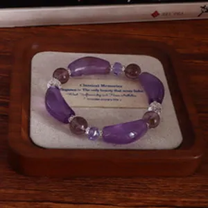 Nahaufnahme eines 14 mm Natur-Amethyst-Perlenarmbands auf einem Vintage-Holztablett