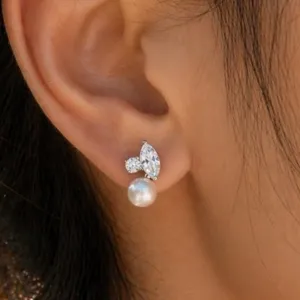 Detailaufnahme eines eleganten Silberohrrings mit Markis-Kristall und Rundperle am Ohr