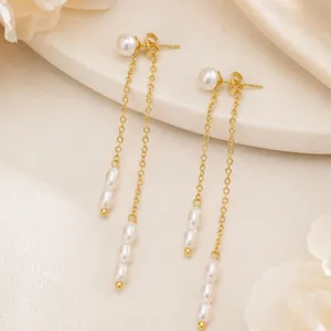 Makrodetail eleganter langer Quastenohrringe mit glänzenden Perlenimitationen in Gold