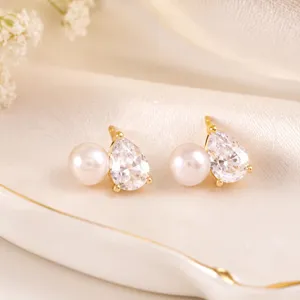 Nahaufnahme eleganter goldener Ohrstecker mit runder Perle und Zirkonia in Tropfenform