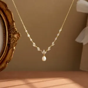 Detailansicht einer eleganten vergoldeten Halskette mit weißer Tropfenperle und Kristallen