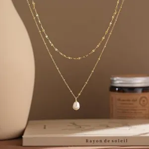 Detailansicht einer goldfarbenen Schichtkette mit einem Tropfenperlenanhänger