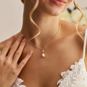 Elegante Detailansicht einer Goldkette mit doppelten Perlenanhängern an einem Model