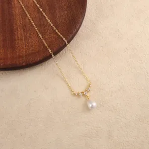 Detailaufnahme einer eleganten goldenen Halskette mit weißem Kunstperlenanhänger