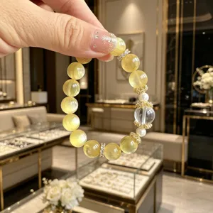Nahaufnahme eines goldenen Glimmerarmbands mit durchscheinenden Perlen und Kristallen