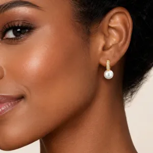 Detailansicht eines eleganten goldenen Creolen-Ohrrings mit weißer Perle an einem Model